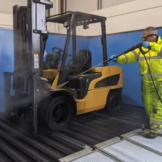 Fork lift truck being power washed on water reclaim wash pad pro