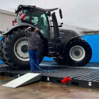 Tractor being power washed on water reclaim wash pad pro